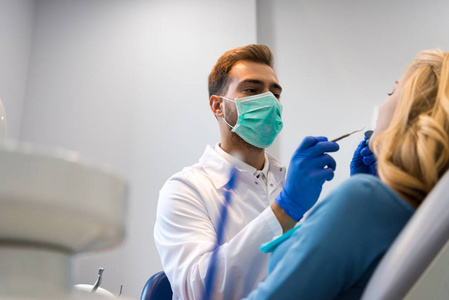 牙医的底部视图在面膜检查牙齿的女性客户
