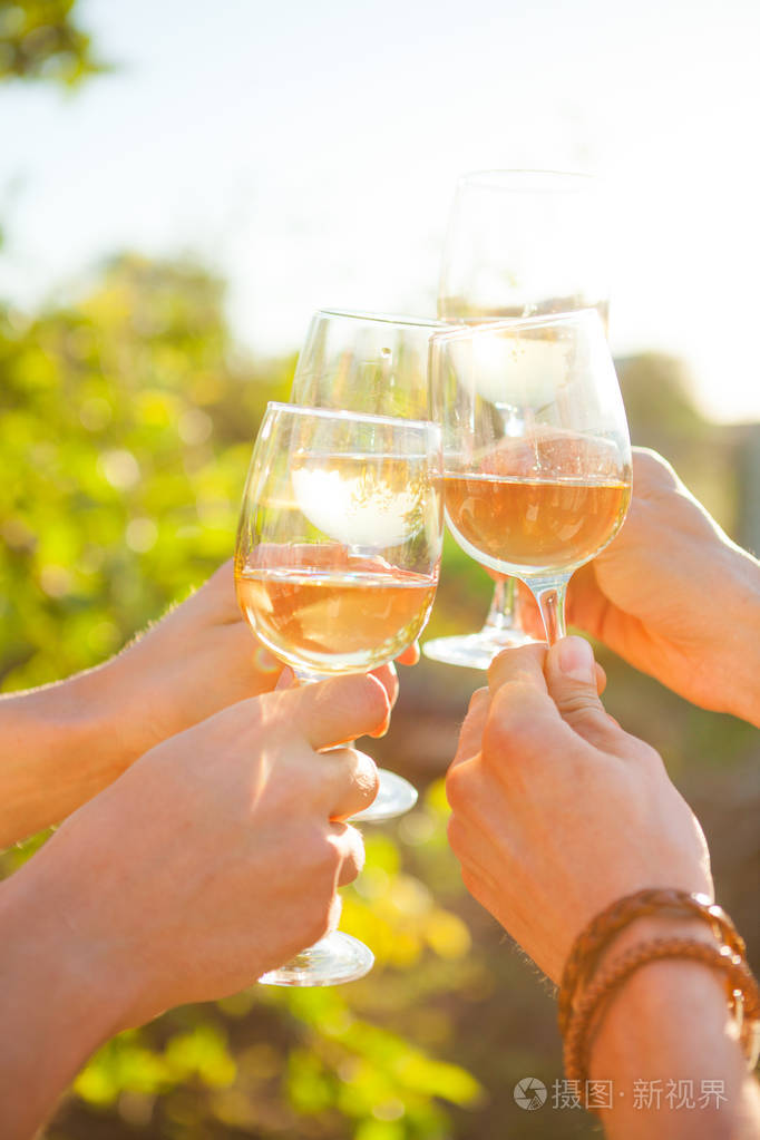 在花园野餐时手里拿着白葡萄酒敬酒朋友幸福享受晚餐吃的概念