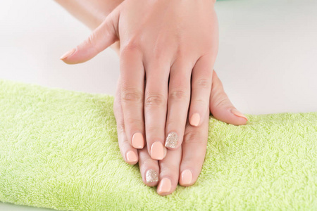 美丽的女人手上的指甲在绿色毛巾在美容工作室。特写, 选择性聚焦