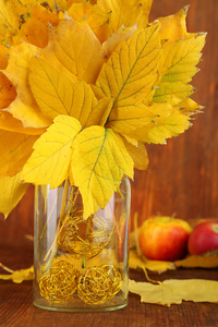 明亮的秋天叶子插在花瓶里的木桌特写