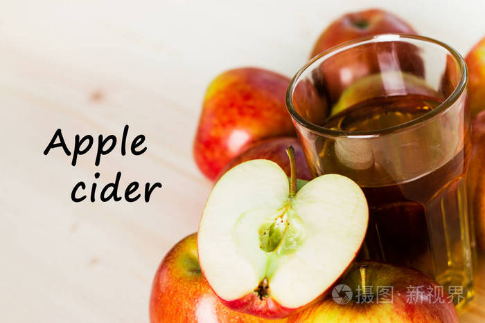 一杯新鲜苹果酒和半个苹果在秋天苹果附近。木质背景, 文本苹果酒。秋季背景