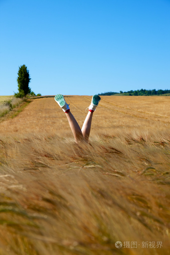 一个年轻的女人,躺在草地上,她的双腿在空中