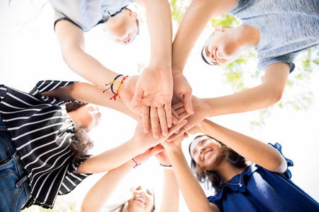 低角度视图组十几岁的男孩和女孩把他们的手放在一起堆叠照片