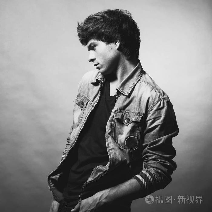 穿牛仔夹克的男人, 摆在灰色背景上.黑白照片