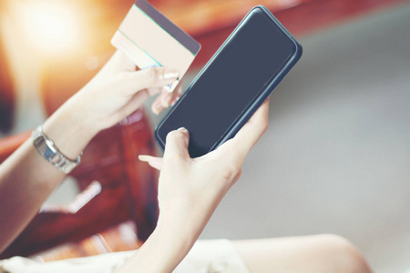 女子亚洲使用电话和信贷卡购物在线 选择性焦点手上