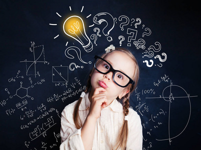 小孩子数学的学生在背景下用灯泡和数学公式思考.孩子的想法照片