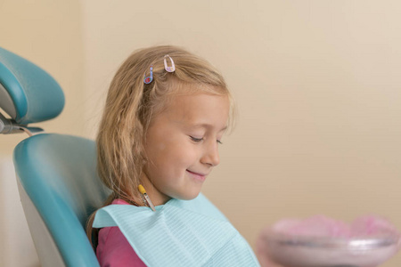 在牙科治疗后, 小女孩坐在牙医旁边的椅子上。小女孩坐在牙医的办公室里