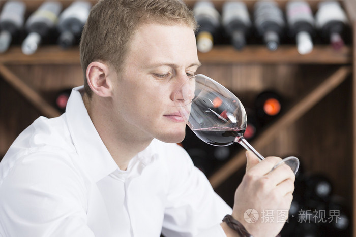 年轻男人嗅到一杯红酒