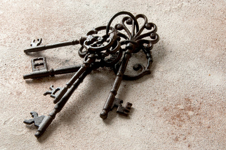 一堆旧的铸铁钥匙在具体的背景上。复制文本空间