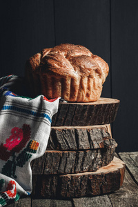 新鲜出炉的面包在黑暗的木质背景, 树桩和布。复活节面包