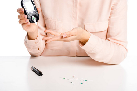 女孩的裁剪图像在白糖尿病概念血糖仪查出的血液中葡萄糖的水平