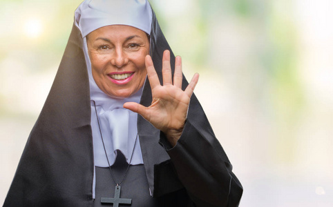 中世纪高级基督教天主教修女妇女在孤立的背景显示和指向手指数五, 而微笑着自信和快乐