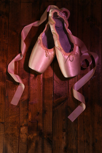 芭蕾舞团备脚尖鞋在木制的背景上