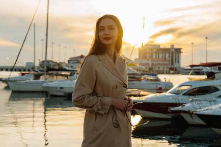 优雅的年轻女子长厚的头发享受夕阳在海港和摆姿势