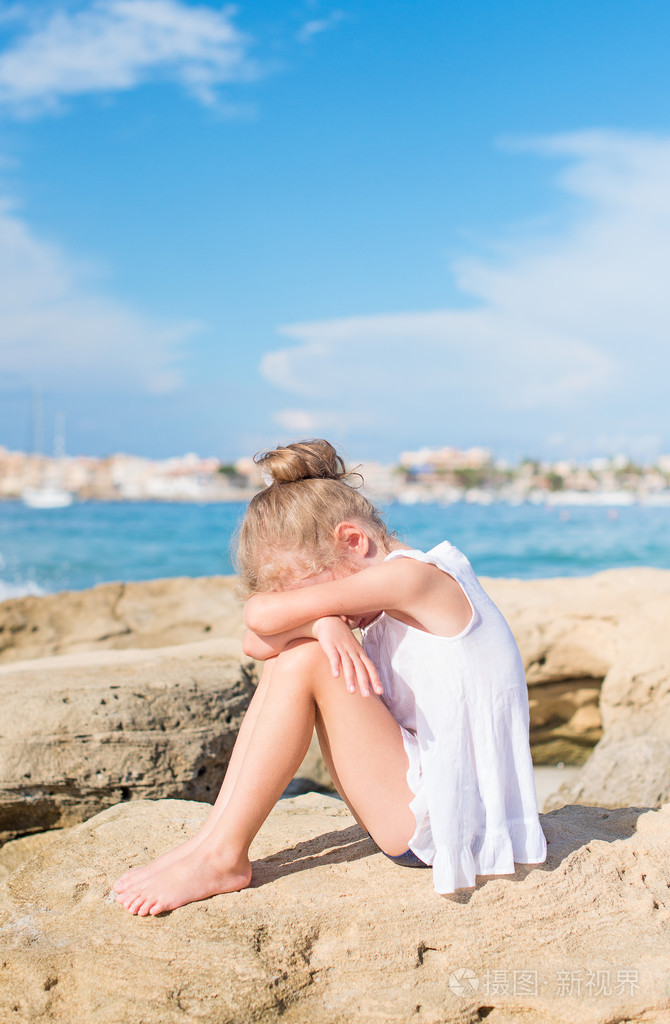 悲伤的小女孩坐在沙滩上。文本的地方