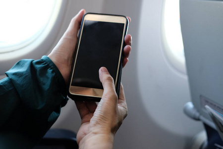 在飞机上使用智能手机的女性旅行者。在飞机上手持手机的乘客。旅行和连接
