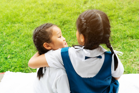 两个小亚洲女孩姐妹拥抱快乐的帖子在校服, 回到学校概念