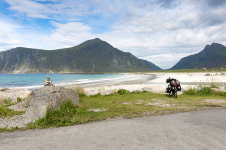 自行车与行李站在戏剧性的山前在挪威海滩, 罗弗敦, Nordland, 挪威