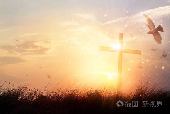 剪影基督徒十字架在草在日出背景以奇迹明亮的照明,宗教和崇拜概念