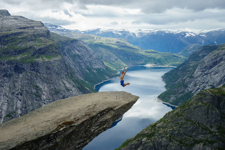 年轻人跳在边缘 Trolltunga。挪威