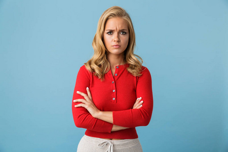 沮丧的金发碧眼的女人20多岁的肖像穿着红色衬衫皱眉隔离在蓝色背景在演播室