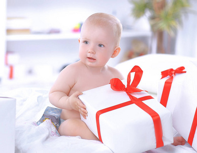 漂亮的婴儿玩的礼品盒坐在沙发上