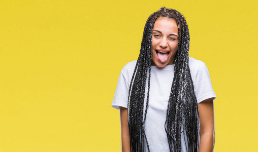 年轻的编织头发非洲裔美国女孩在孤立的背景伸出舌头出来的喜悦与有趣的表达。情感概念