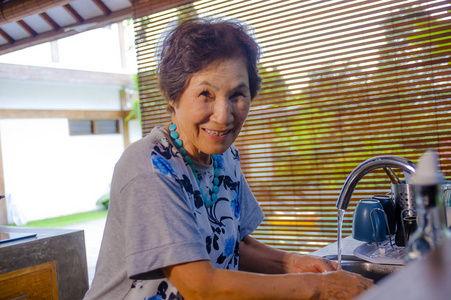 资深快乐亚洲日本人的生活方式肖像退休了, 在家里做饭的女人独自一人整齐整洁的洗盘子微笑在家务的概念