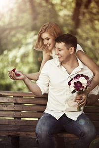 爱与婚礼概念。坐在公园的幸福小两口