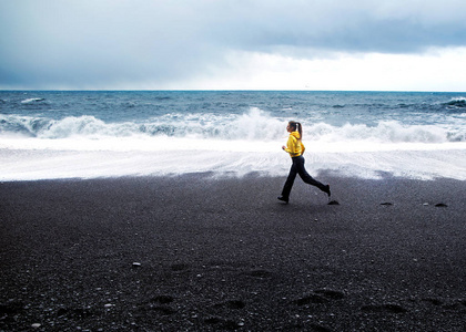 在冰岛的大西洋沿岸, 女孩沿着海滩奔跑。
