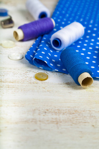 缝纫配件和蓝色织物的木质背景。织物测量胶带针脚纽扣和螺纹