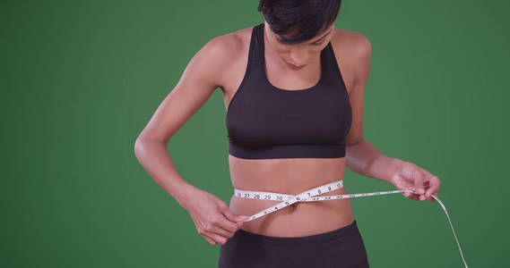 在绿色屏幕上成功饮食后测量腰围大小的妇女