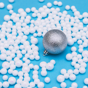 银色圣诞节球与白色珍珠散落在蓝色背景照片