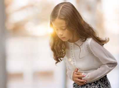 儿童消化不良黑发西班牙裔女孩用手在胃因为消化不良, 痛苦的病症感觉