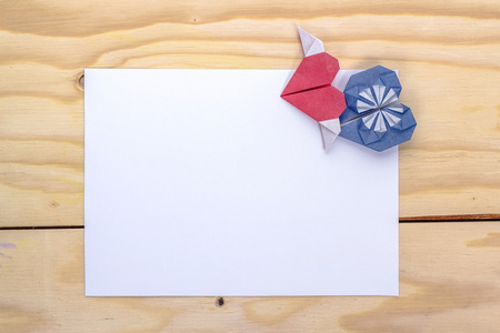 情人节礼物卡与折纸蓝色和红色爱心木制的桌子上
