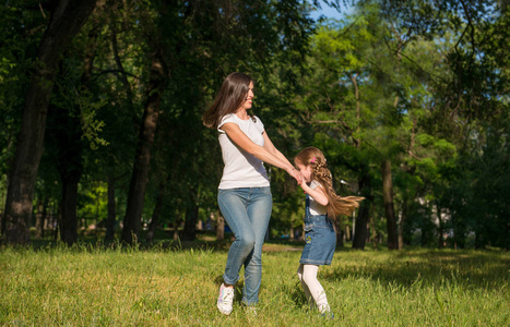 妈妈女儿牵手背影欧美妈妈和女儿手牵手在草坪上旋转照片