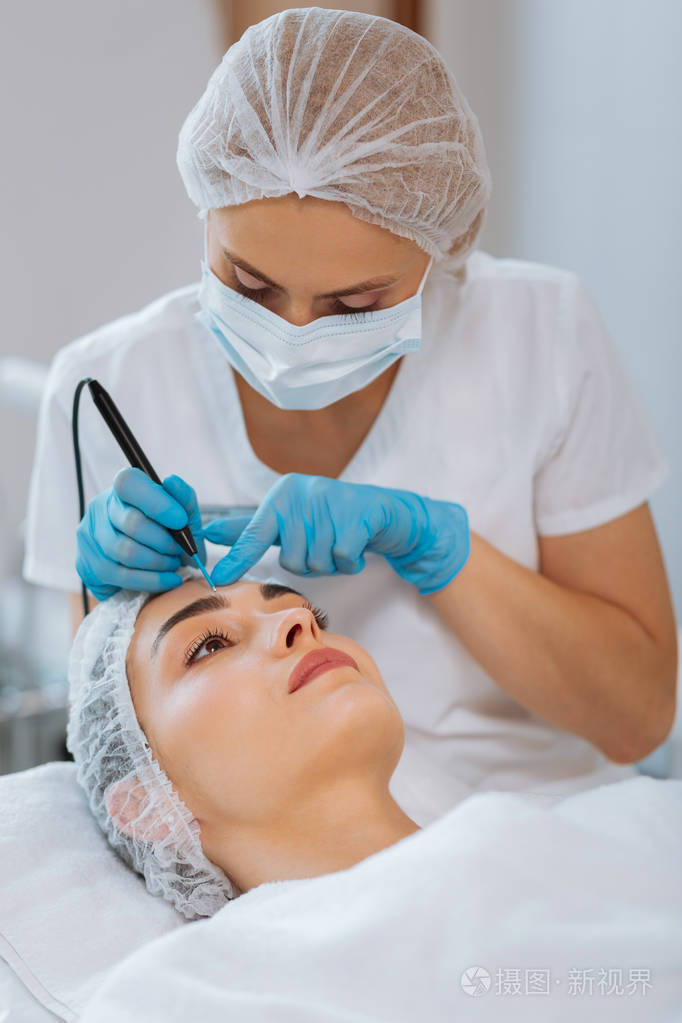 严重熟练的女性皮肤科医生去除痣