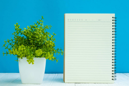 空白笔记本在白色木桌前面蓝色墙壁背景与拷贝空间为添加文本或广告词, 菜单样机