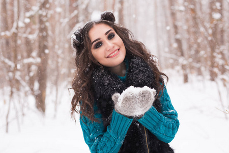美丽和人的概念快乐的黑发女人在冬天的森林是微笑着, 并举行着雪在她的手中