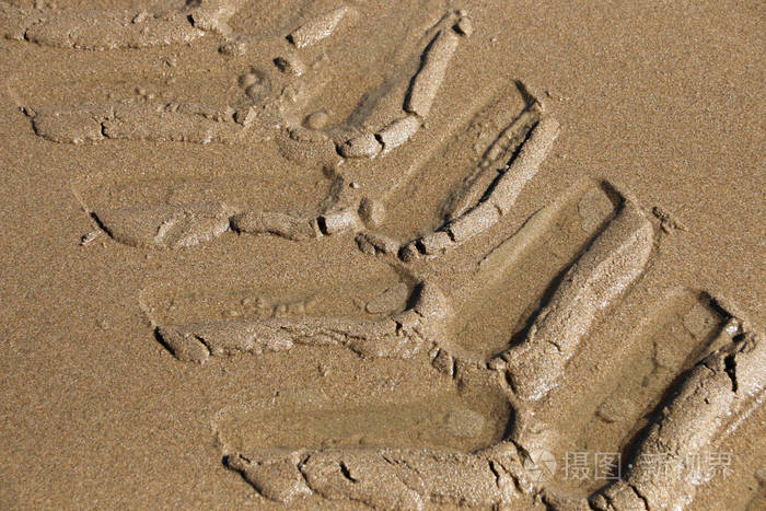 在湿沙滩砂中留下的拖拉机轮胎的压痕