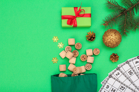 棋盘游戏。木莲花桶与袋和游戏卡的游戏在, 圣诞冷杉树枝, 锥, 玩具球和礼品盒在绿色背景。顶视图