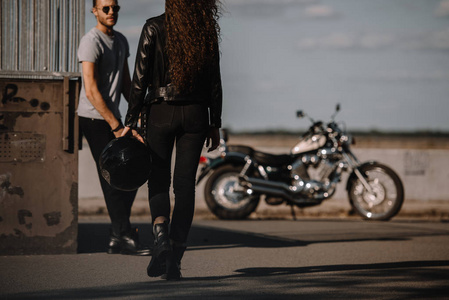 女孩拿着头盔, 去男朋友与古典摩托车