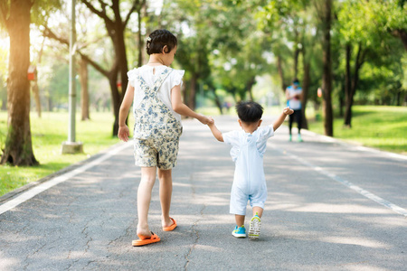 亚洲姊妹与小朋友牵手走在公园的路上, 阳光明媚。