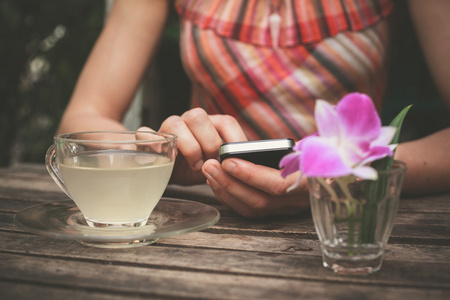 年轻女人喝茶，用她的手机