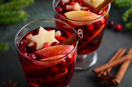 圣诞节热葡萄酒与苹果, 橙和蔓越莓。用杉木树枝蔓越莓和香料装饰的假日概念