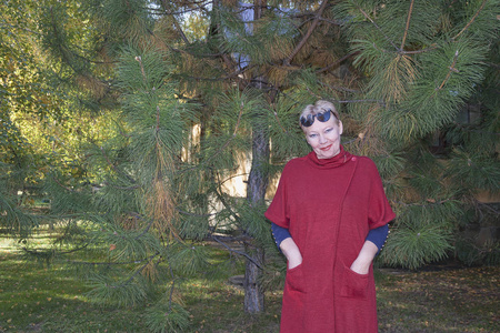 成熟的女人在红色开衫附近克里米亚松树与长针