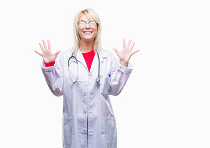 年轻美丽的金发医生妇女穿医疗制服在孤立的背景显示和指向与手指数字十同时微笑自信和快乐