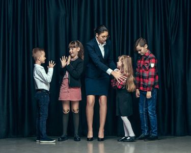 可爱时尚的孩子在黑暗的工作室背景。美丽的少女和男孩站在一起