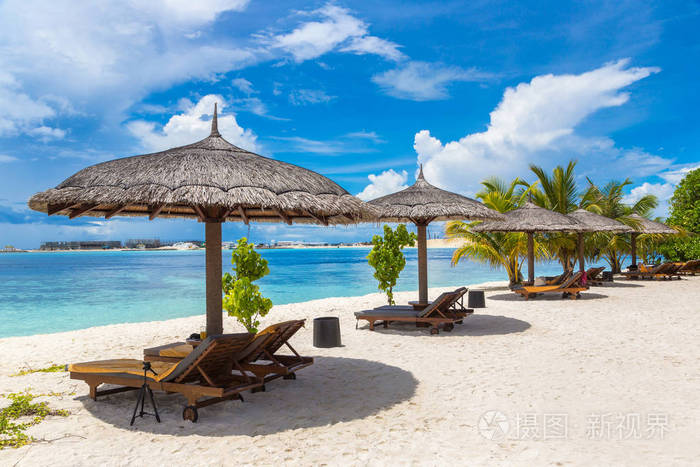 夏季日在马尔代夫热带海滩上的木制日光浴和雨伞