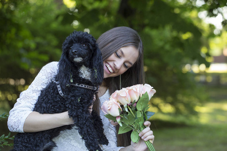 在公园里和她的狗一起享受的年轻女子。惊讶她收到的花朵。选择性聚焦与景深小